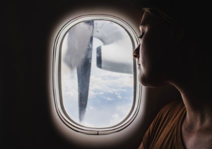 woman wearing brown scoop-neck sitting near airplane window while sleeping during flight photo