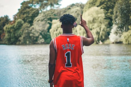 man standing facing body of water while raising his right arm photo