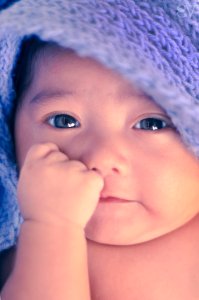 A happy baby with a blanket over her head.