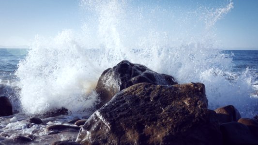 seashore splashed on rock during daytime photo