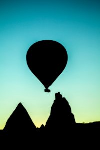 silhouette of hot air balloon flying above rock formation photo