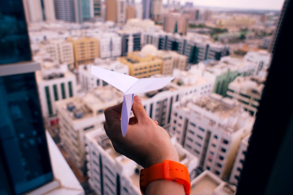 shallow focus photography of person holding paper plane