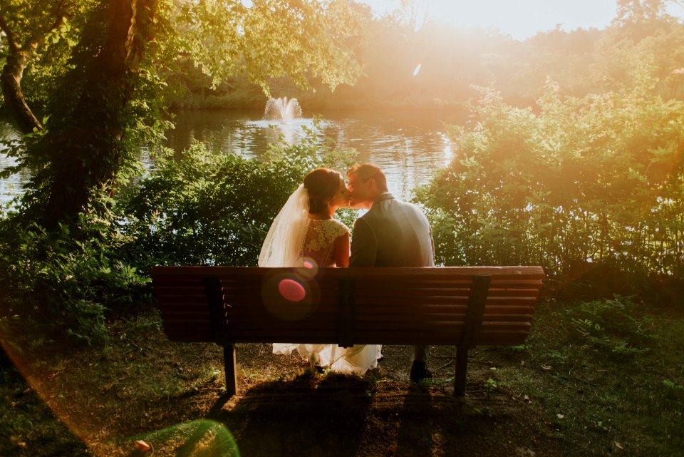 newlywed sitting on bench white kissing