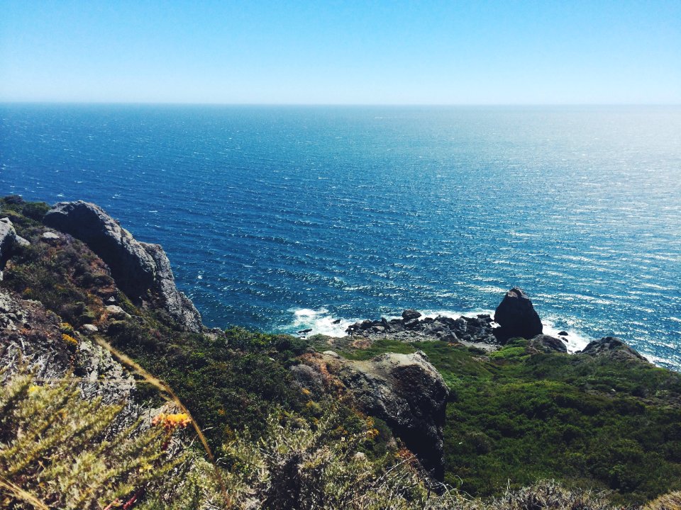 person sitting on cliff near body of water