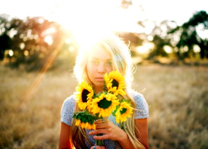 portrait photography of woman holding bouquet of sunflowers photo