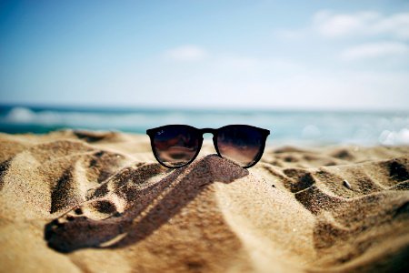 black Ray-Ban Wayfarer sunglasses on beach sand photo