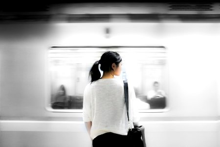 woman in white elbow-sleeved shirt standing near white train in subway photo