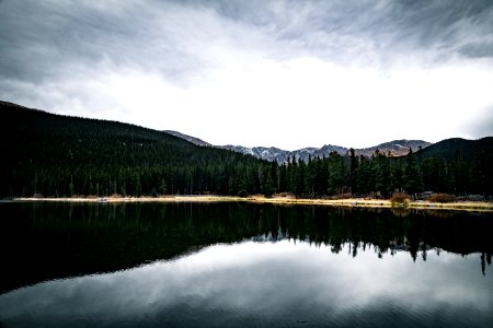 body of water beside trees and mountain with cloudy sky photo