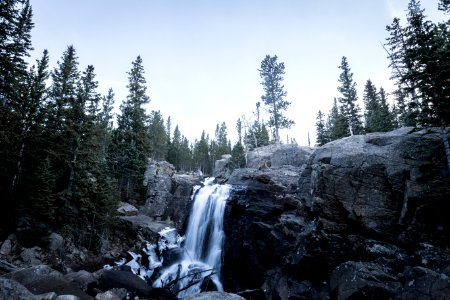 timelapse photography of waterfall surrounded by trees under blue sky at daytime photo