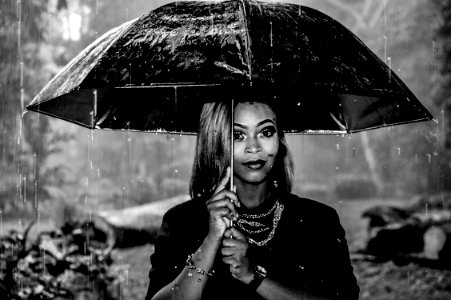 grayscale photography of woman under umbrella at rainy season