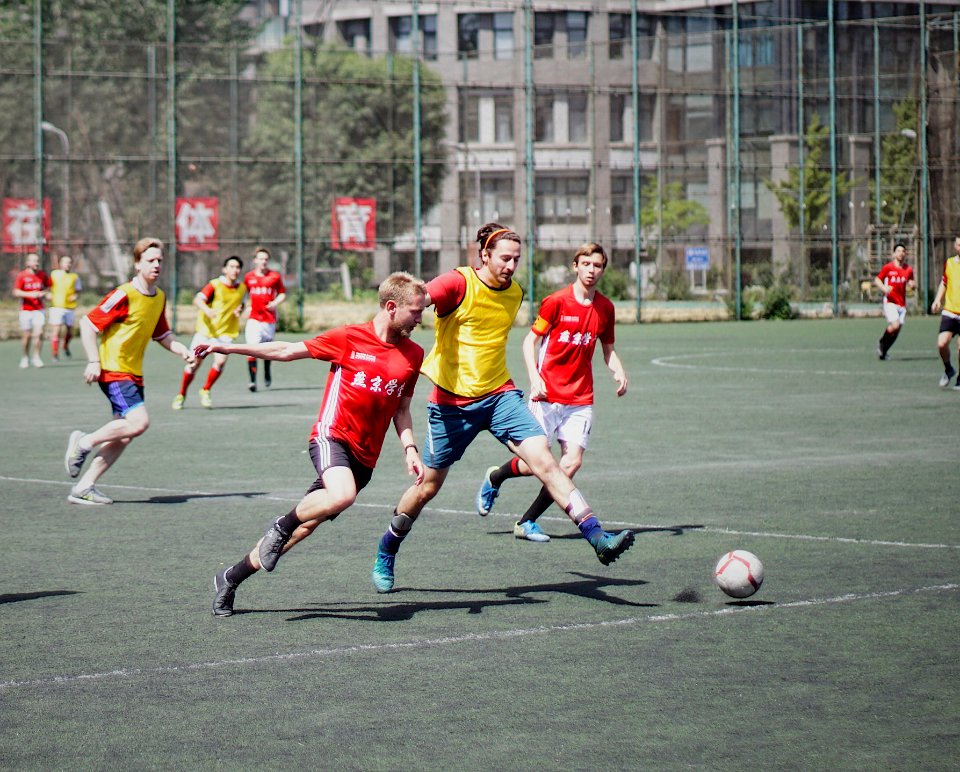 men playing soccer on field with fence