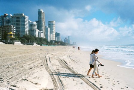 people walking on seashore near concrete buildings during daytime photo