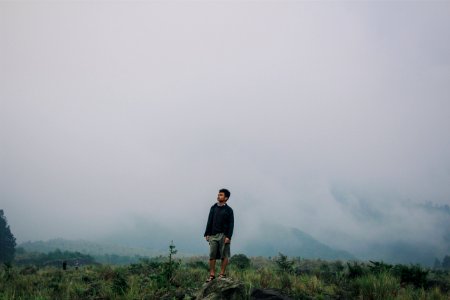 man standing on gray stone under cloudy sky photo