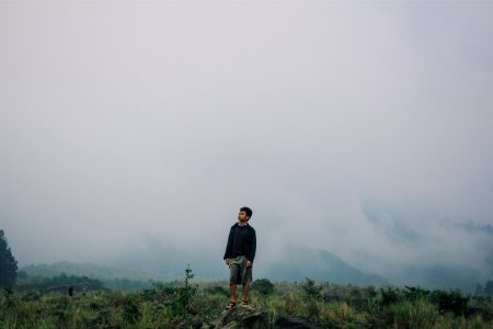 man standing on gray stone under cloudy sky