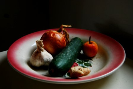 onion, garlic, ginger, and green vegetable on round white and red plate photo