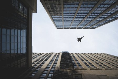 worm's view photo of fighter jet flying above building photo