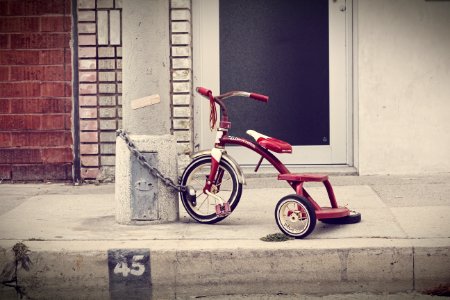 red and white Radio Flyer trike chained on stone post photo