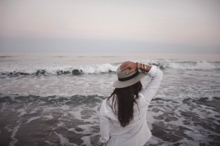 woman holding hat beside body of water photo