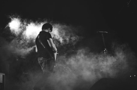 grayscale photography of man performing guitar on stage photo