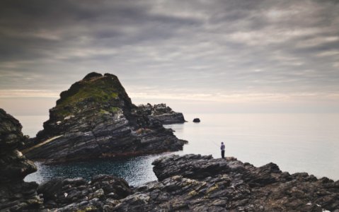 person standing on brown rock formation by the sea during daytime photo