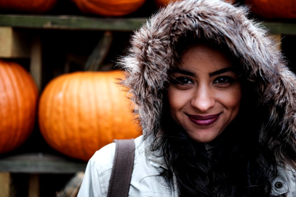 woman in front of orange pumpkin posing