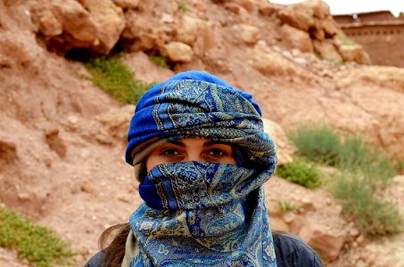 masked woman standing beside rock