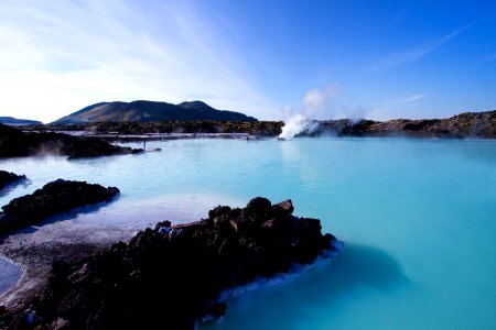 calm water beside mountain under white clouds and blue sky photo