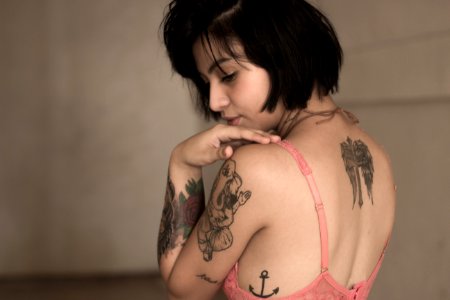 standing woman wearing pink bra with tattoos