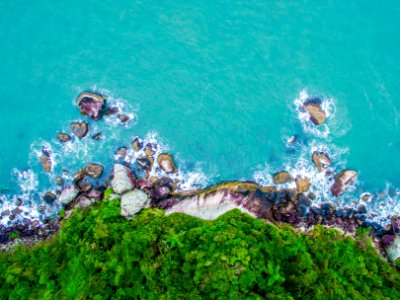 green and gray cliff near body of water in high angle photography