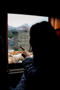 woman in gray knitted sweater looking and pointing at the window photo