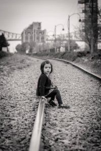 woman in black jacket sitting on train rail during daytime photo