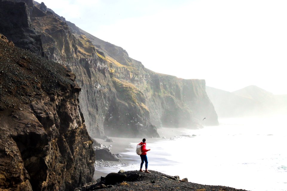 person standing on cliff near body of water during daytime photo