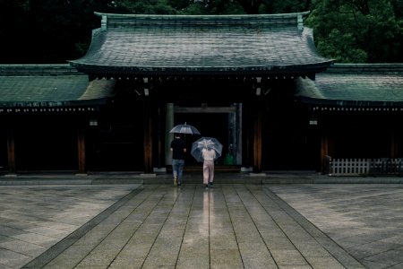 two people holding umbrellas near brown building during rainy season