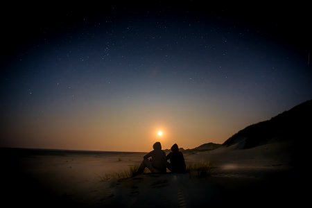 silhouette of two person sitting during golden hour photo