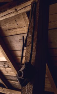 black point-and-shoot camera hanging on a brown wooden bar photo