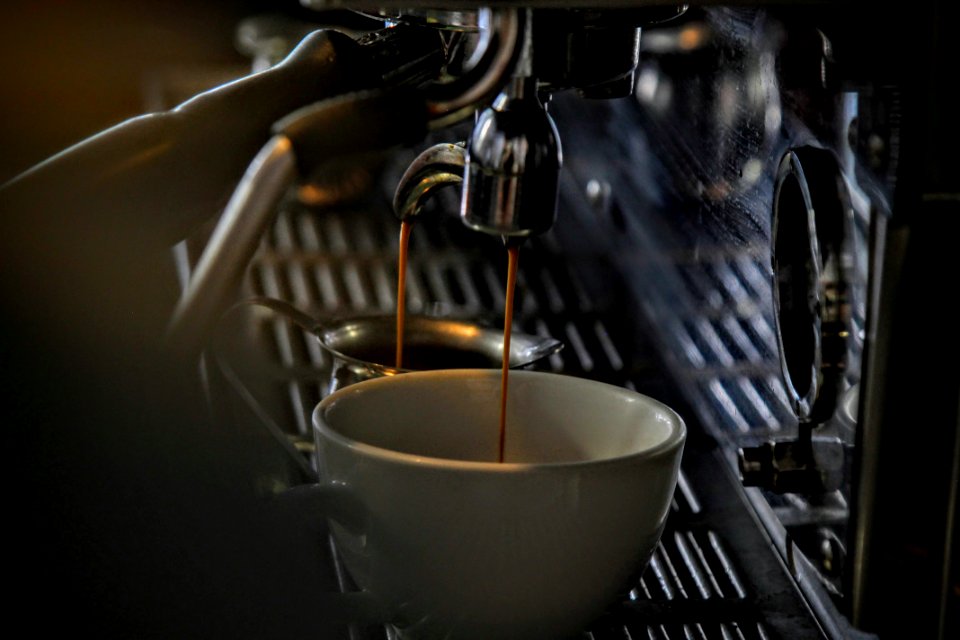Espresso dripping into a porcelain mug from a steel machine