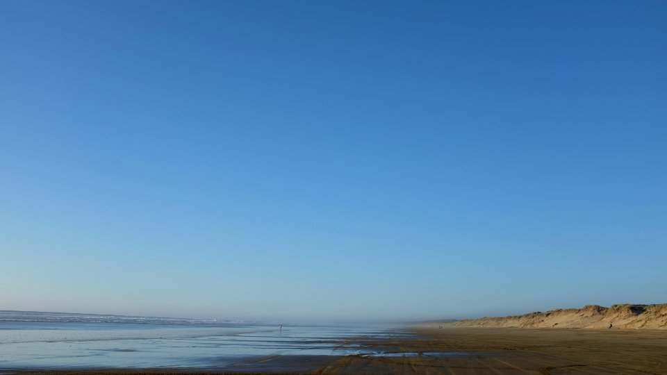 body of water and gray seashore under blue sky photo