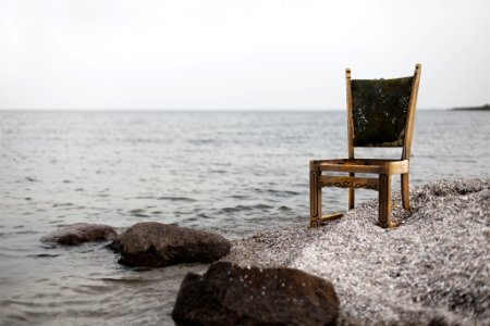 brown wooden parsons chair on gray beach sand photo