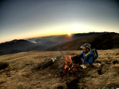 man laying on brown grass infront of bonefire during sunrise photo