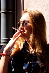 close-up photography of woman holding cigarette stick during daytime photo