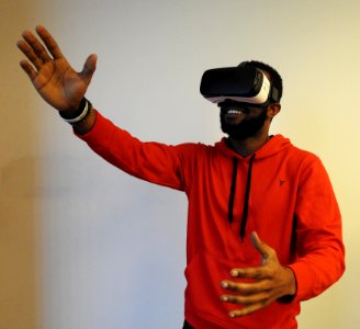 man wearing white VR headset while lifting right hand photo