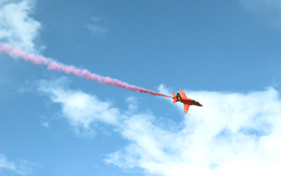 photo of jet plane with red smoke flying on air