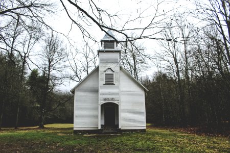 photo of white wooden chapel surrounded by trees during daytime photo