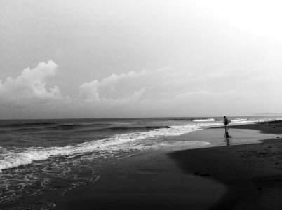 grayscale photography of person standing on seashore photo