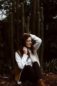 smiling woman wearing brown and white coat sitting beside green cacti plants photo