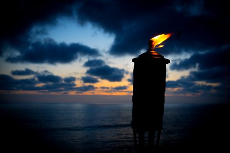 lighted tiki torch near sea at night photo