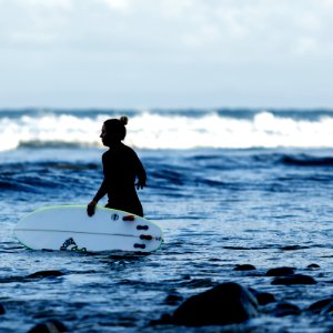 woman holding white surfboard on body of water photo