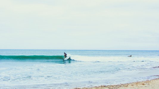 person surfing using white surfboard during daytime photo