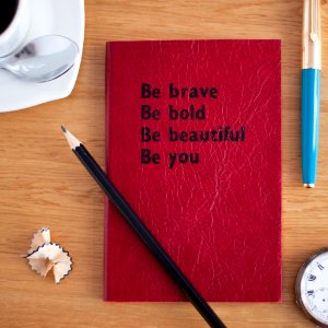 A red book with black titling that says "Be brave Be bold Be beautiful Be you." photo