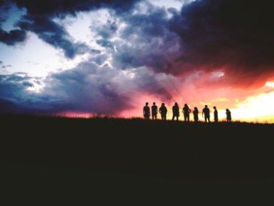 silhouette of nine persons standing on the hill photo
